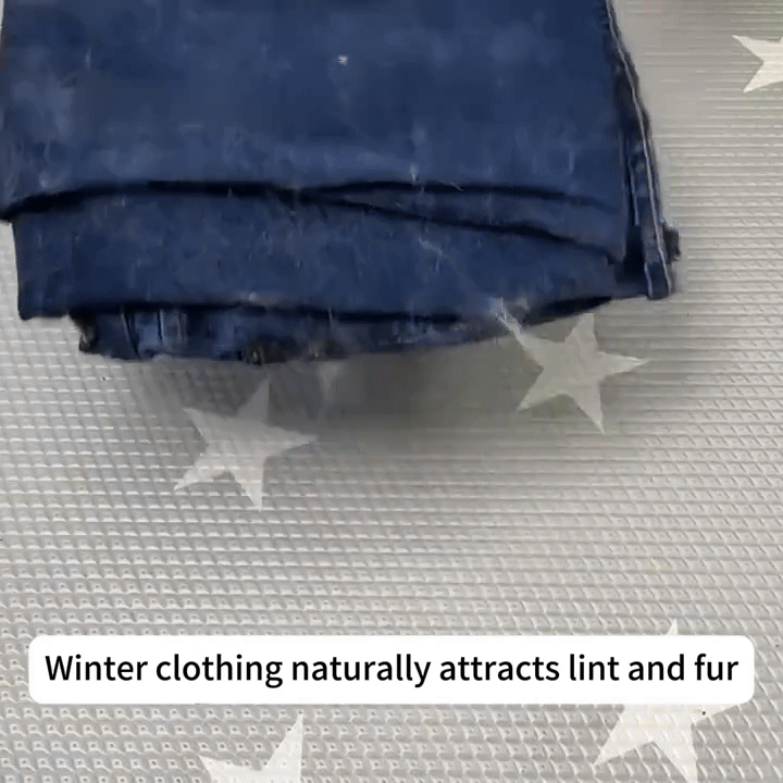 Folded dark blue jeans attracting lint and fur on star-patterned fabric surface