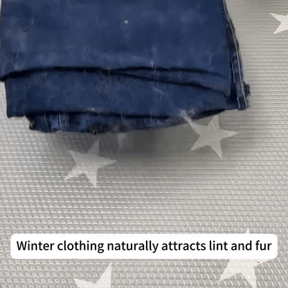 Folded dark blue jeans attracting lint and fur on star-patterned fabric surface